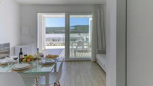 Une chambre moderne avec une table à manger pour deux personnes, un canapé et un balcon offrant une vue sur le paysage.