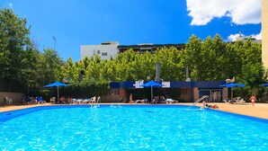 A swimming pool with lounge chairs and umbrellas, surrounded by trees and buildings. - Nice studio near the Beach - AA/CC - UHC ALBORAN 292 (Salou)