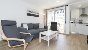 A modern living room with a grey sofa, a wooden chair, and a white coffee table. - Nice studio near the Beach - AA/CC - UHC ALBORAN 292 (Salou)
