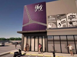 Un hotel moderno con un llamativo letrero 'Yes Hotel', amplias ventanas y un estacionamiento con coches y personas.
