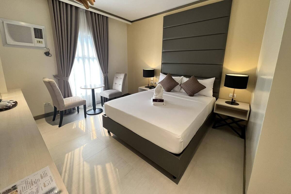 Una habitación de hotel moderna con una cama grande, un escritorio, una silla y una pequeña mesa.
