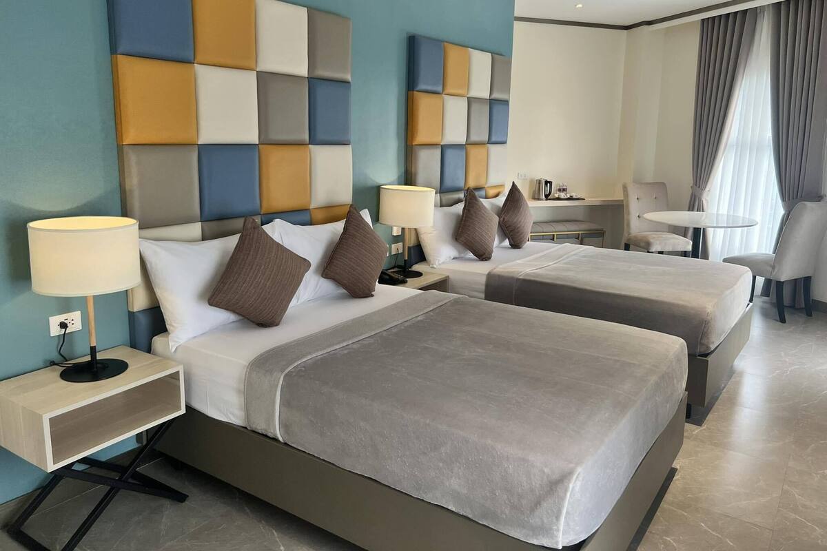 Una habitación de hotel con dos camas, un escritorio, una silla y una mesita.