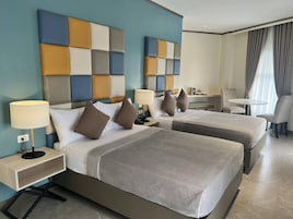 Una habitación de hotel con dos camas, un escritorio, una silla y una mesita.
