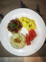Un plato con huevos revueltos, un guiso de carne, arroz y rebanadas de sandía.