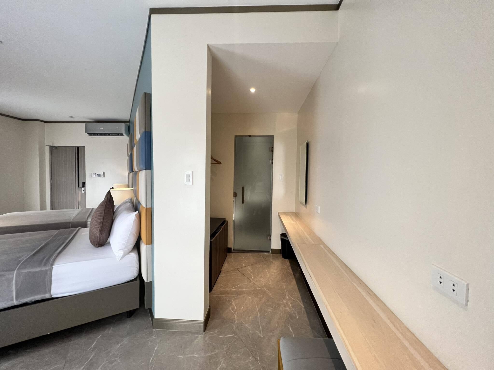 A modern hotel room with a bed, bedside table, and a mirror.