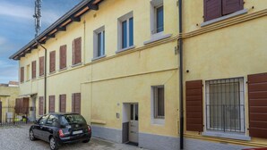 A two-story building with a yellow facade, brown shutters, and a parked car. - GuestHost - Casa Tua- Udine Central Apartment (Udine)