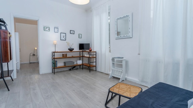 A room with a bed, a desk with a computer, a chair, and a shelf with books and decorative items. - GuestHost - Casa Tua- Udine Central Apartment (Udine)