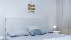 A neatly made bed with a headboard, two pillows, a bedside lamp, and a wall sign with phrases. - GuestHost - Casa Tua- Udine Central Apartment (Udine)