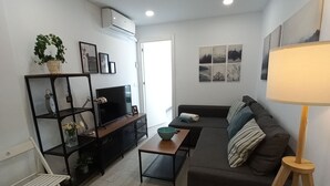 A modern living room with a sofa, a coffee table, a TV, and a bookshelf. - Modern beachfront apartment San Miguel (El Rompido)