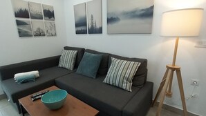 A modern living room with a dark grey sofa, a wooden coffee table, and a floor lamp. - Modern beachfront apartment San Miguel (El Rompido)