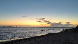 A beach with a calm sea and a clear sky at sunset. - Modern beachfront apartment San Miguel (El Rompido)