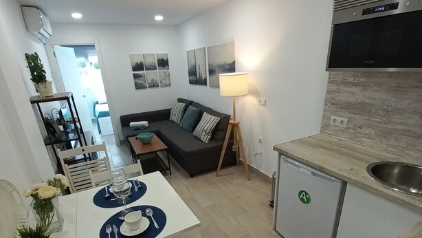 A compact living space with a kitchenette, dining area, and a sofa. - Modern beachfront apartment San Miguel (El Rompido)