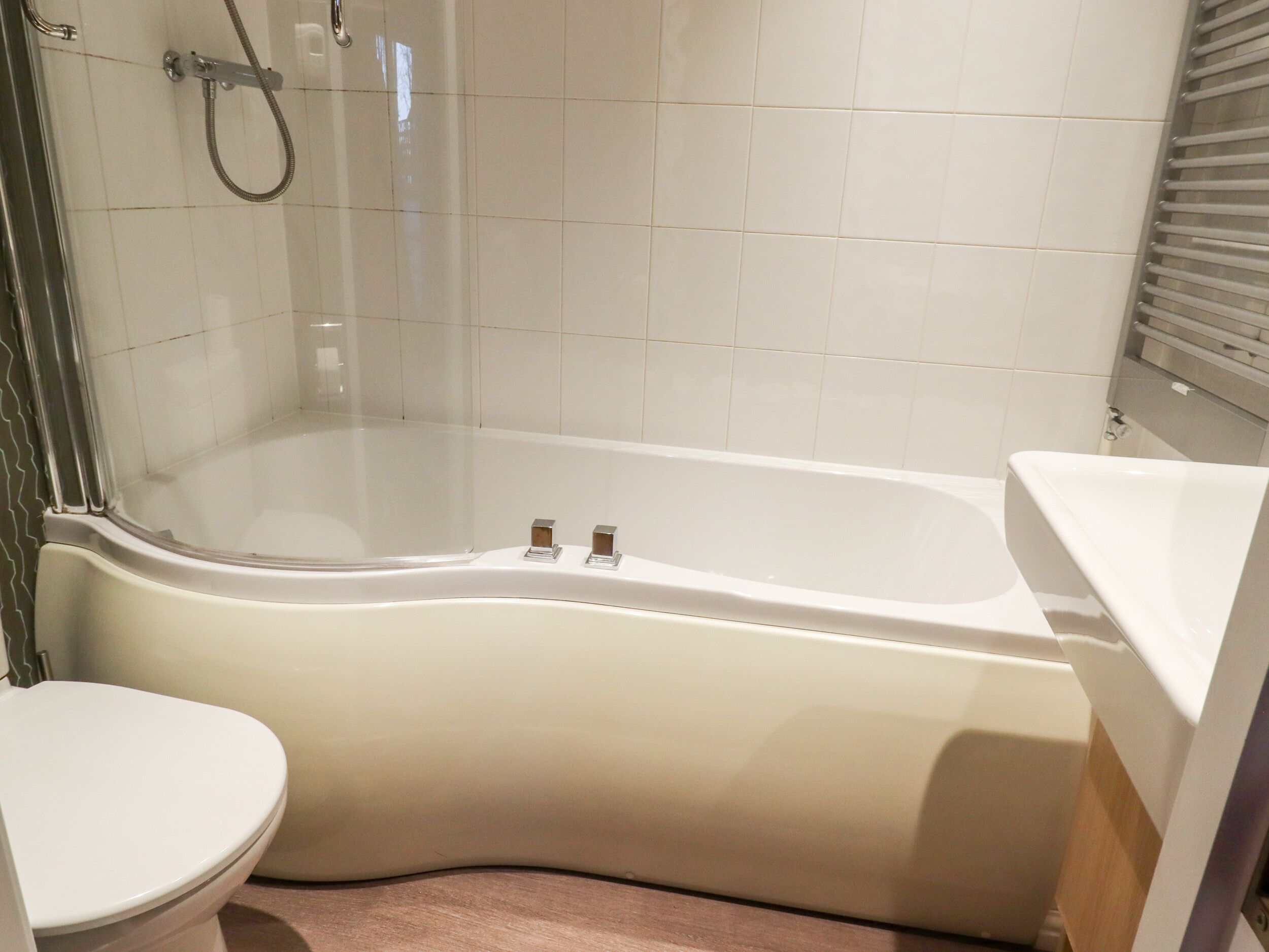 A bathroom with a white bathtub, a toilet, and a shower area.