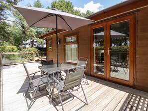 An outdoor patio with a table and chairs, a large umbrella, and a wooden deck. - Washburn Lodge (Harrogate)