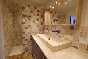 A bathroom with a rectangular sink, a wooden-framed mirror, and tiled walls.