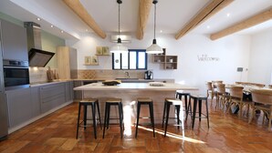 Une cuisine moderne dotée d’un grand îlot central, de tabourets de bar et de poutres en bois.