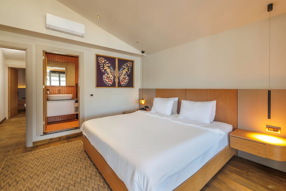 Quarto de hotel moderno com uma cama grande, um closet espaçoso e banheiro com chuveiro e pia.