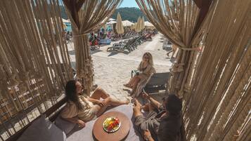 A beachside seating area with a table, chairs, and umbrellas.