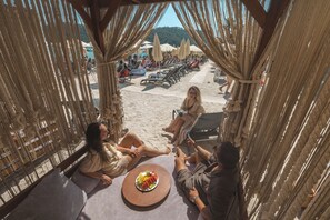 Un espace aménagé sur la plage avec une table, des chaises et des parasols.