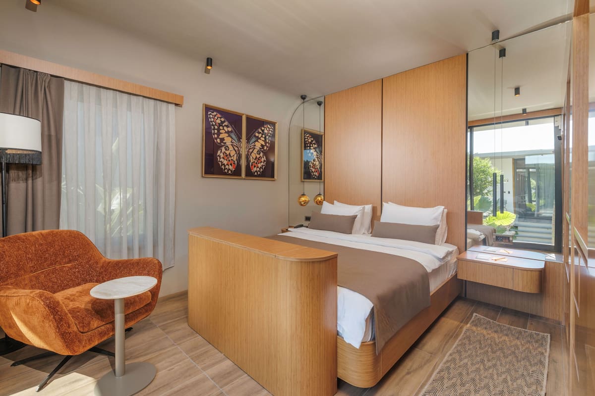 Quarto de hotel moderno com cama, escrivaninha, cadeira e uma janela grande.
