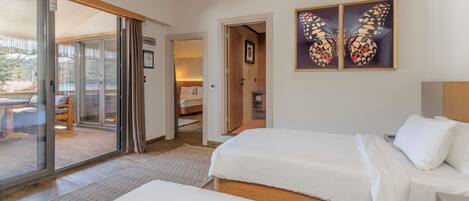 A bedroom with two beds, a sliding glass door to a balcony, and a framed butterfly artwork on the wall.