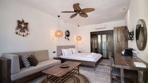 Une chambre moderne avec un lit, un canapé, une table en bois et un ventilateur de plafond.