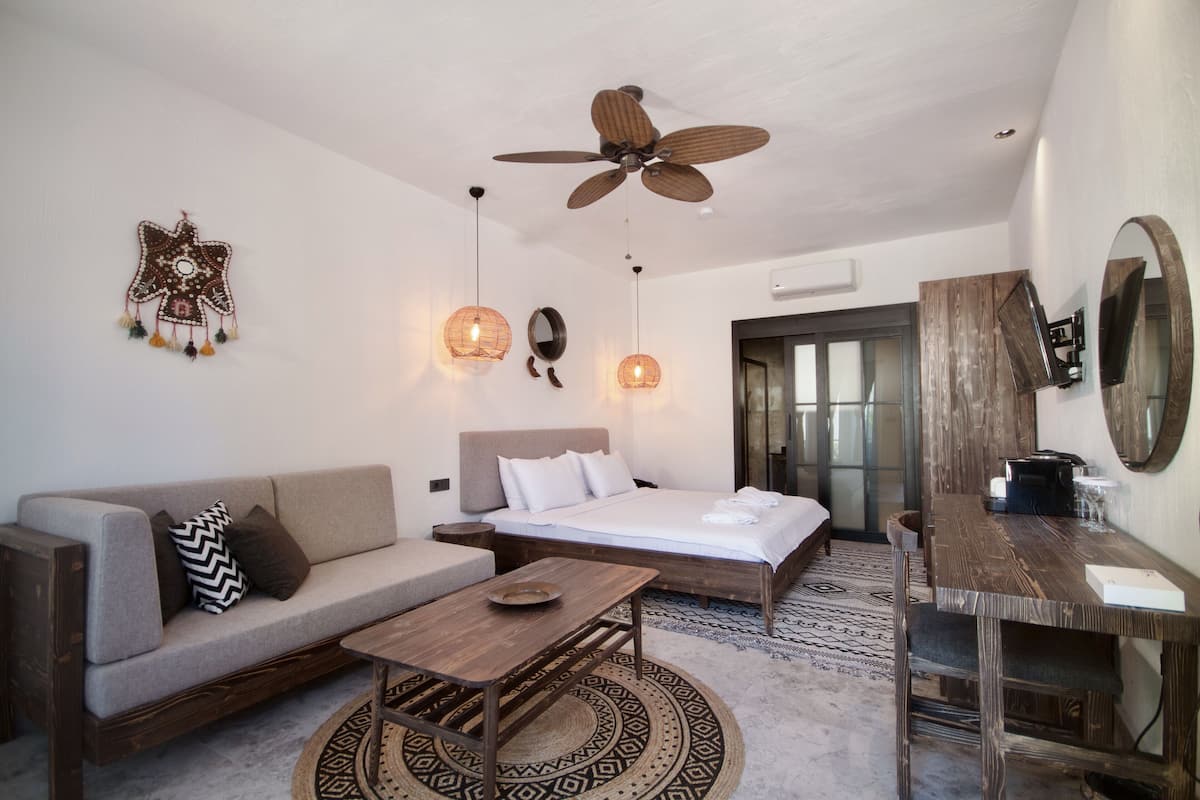 Quarto moderno com cama, sofá, mesa de madeira e ventilador de teto.