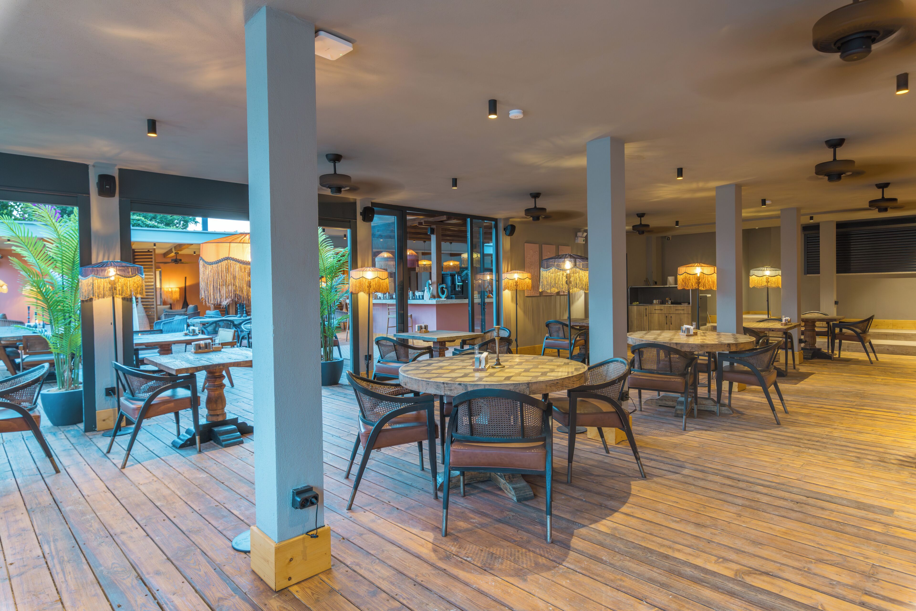 A restaurant with wooden flooring, round tables, and chairs.