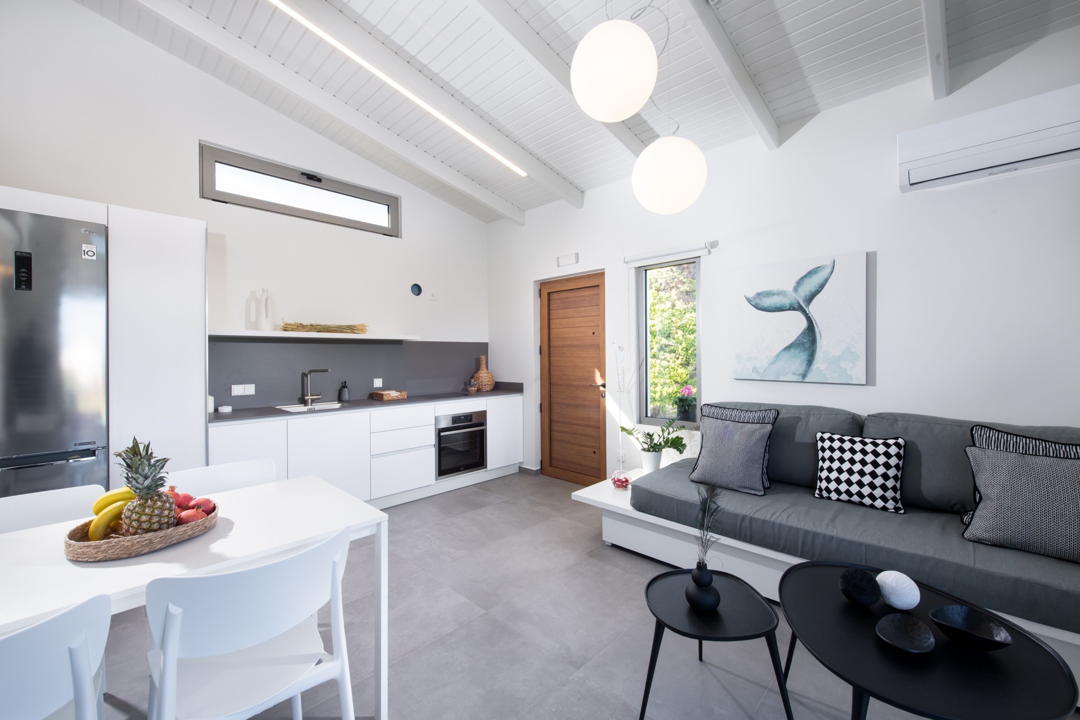 A modern kitchen with white cabinets, a built-in oven, and a stainless steel refrigerator.