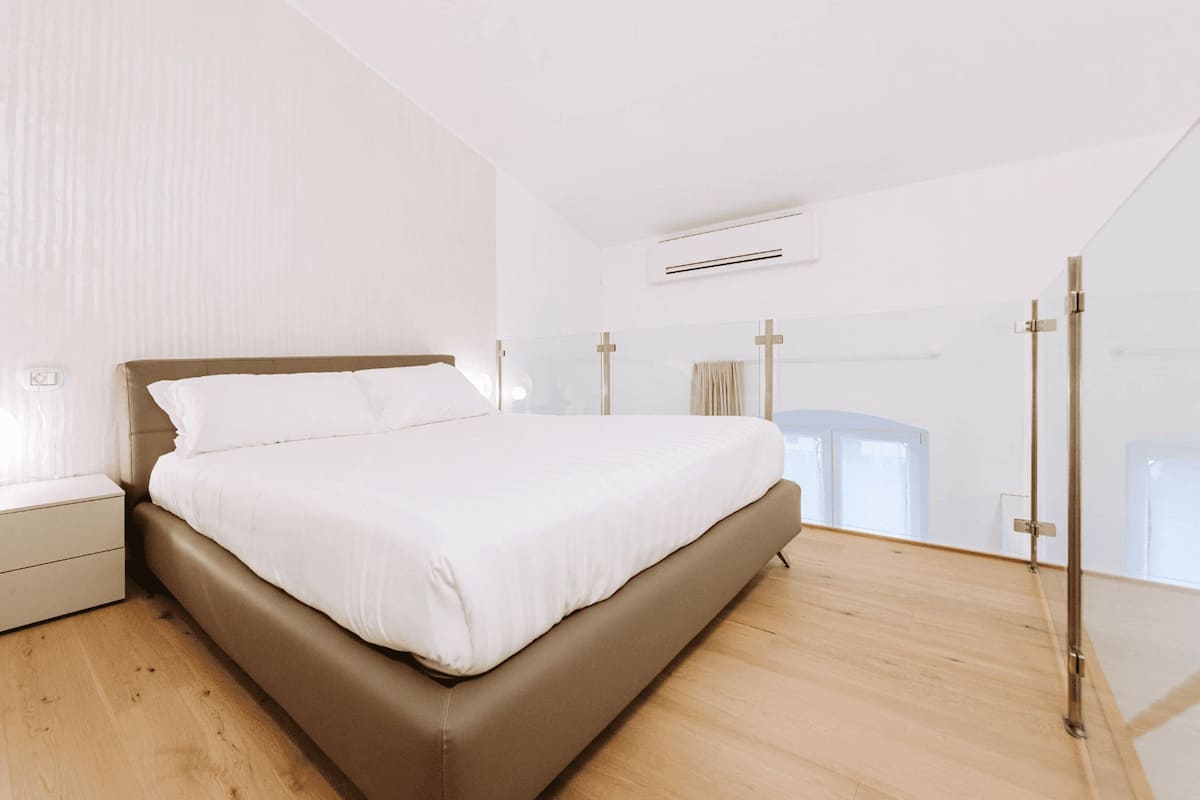 A bedroom with a bed, nightstand, and an air conditioning unit.