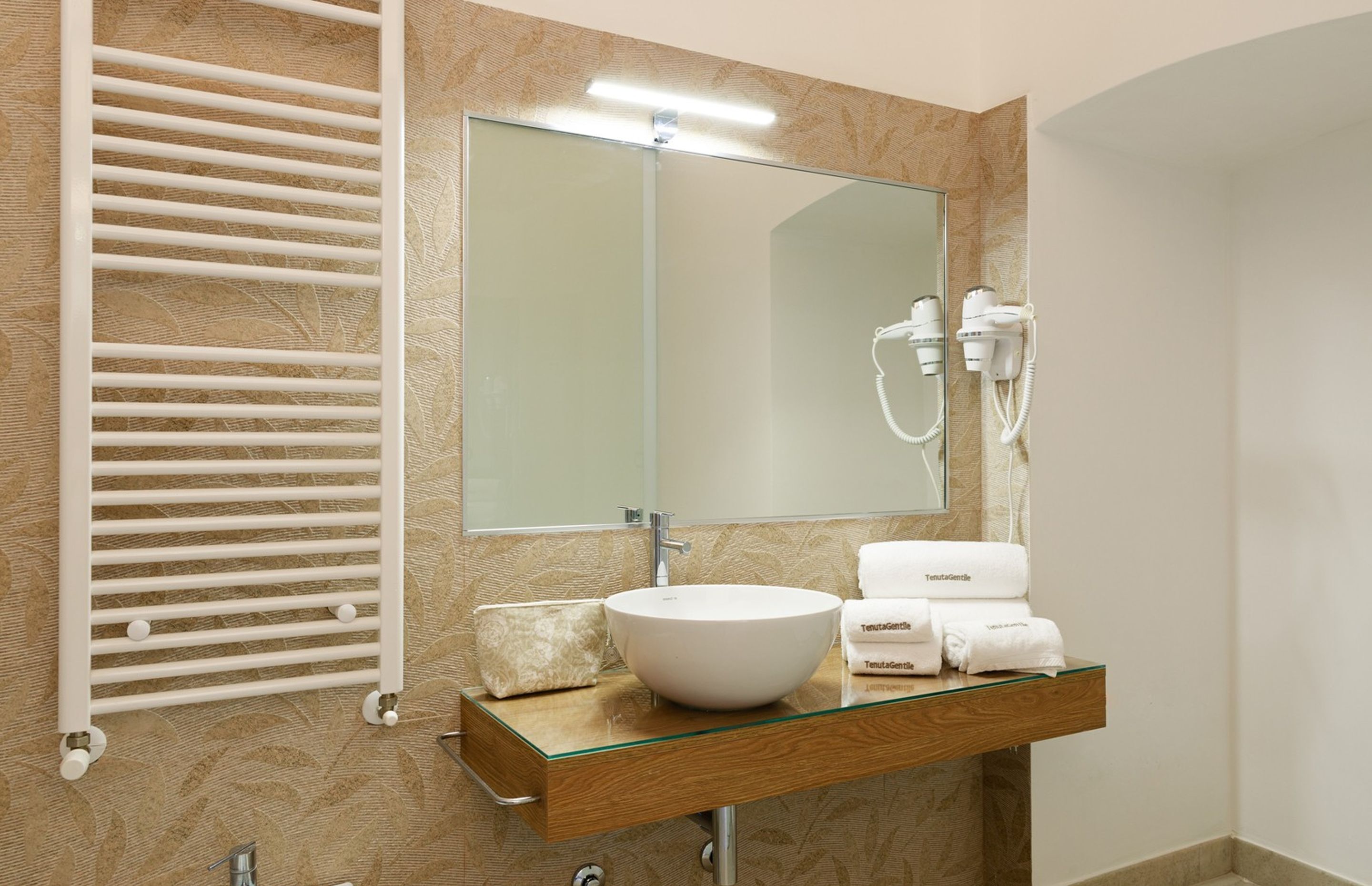 Une salle de bain moderne avec un lavabo en verre, un porte-serviettes, un miroir et un sèche-serviettes.