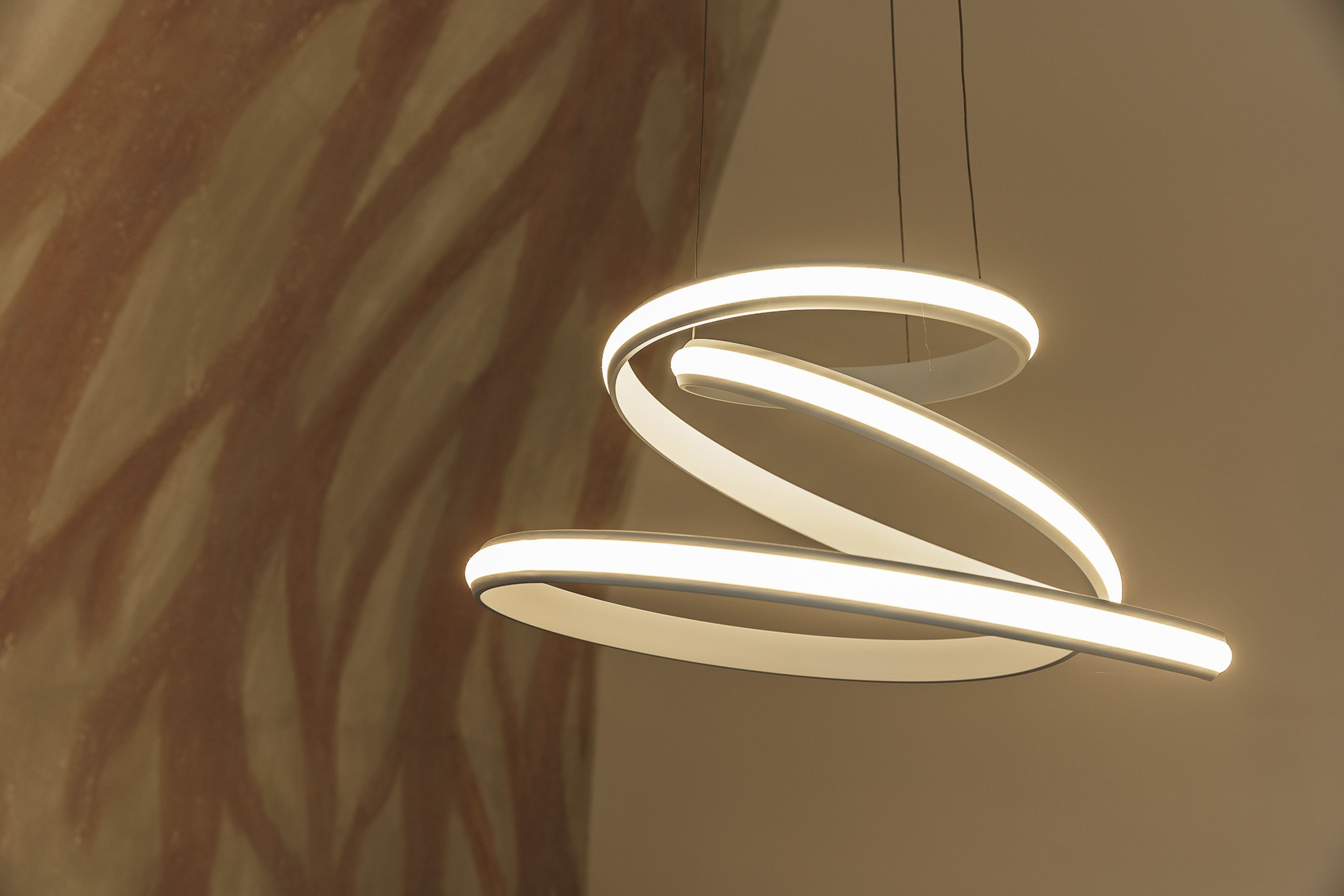 A modern, spiral-shaped light fixture with a smooth, curved design.