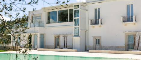 A modern two-story building with a swimming pool in front.