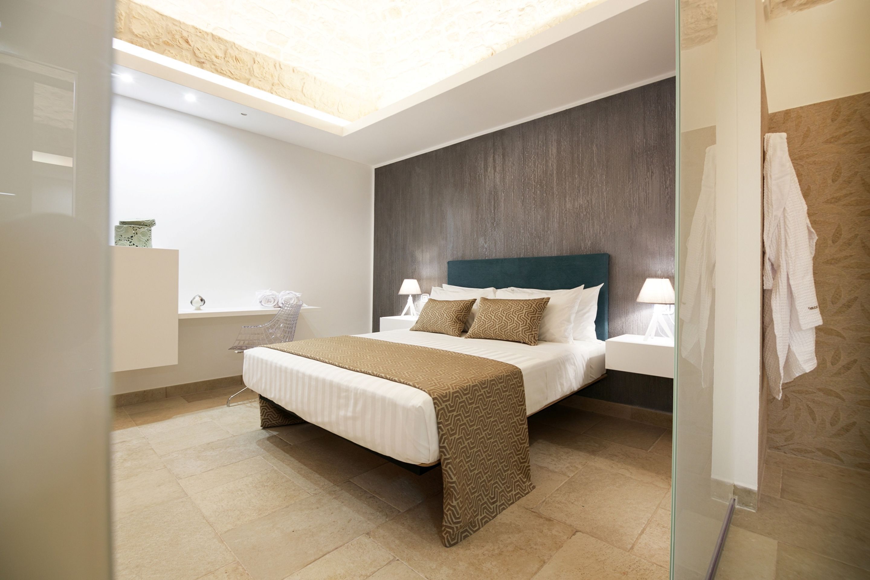 A modern bedroom with a large bed, bedside tables, a skylight, and a shower area.