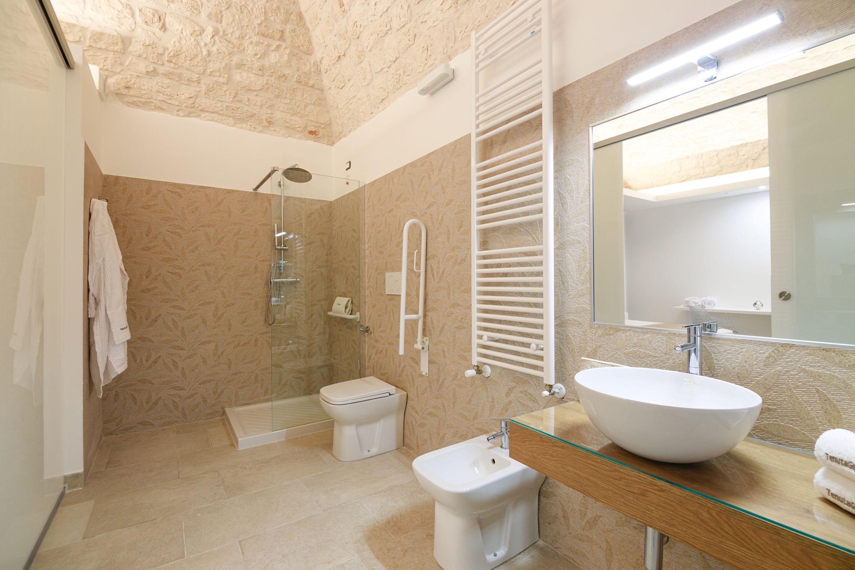 Un bagno moderno con cabina doccia in vetro, lavandino bianco e uno specchio grande.