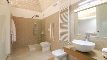 Un bagno moderno con cabina doccia in vetro, lavandino bianco e uno specchio grande.