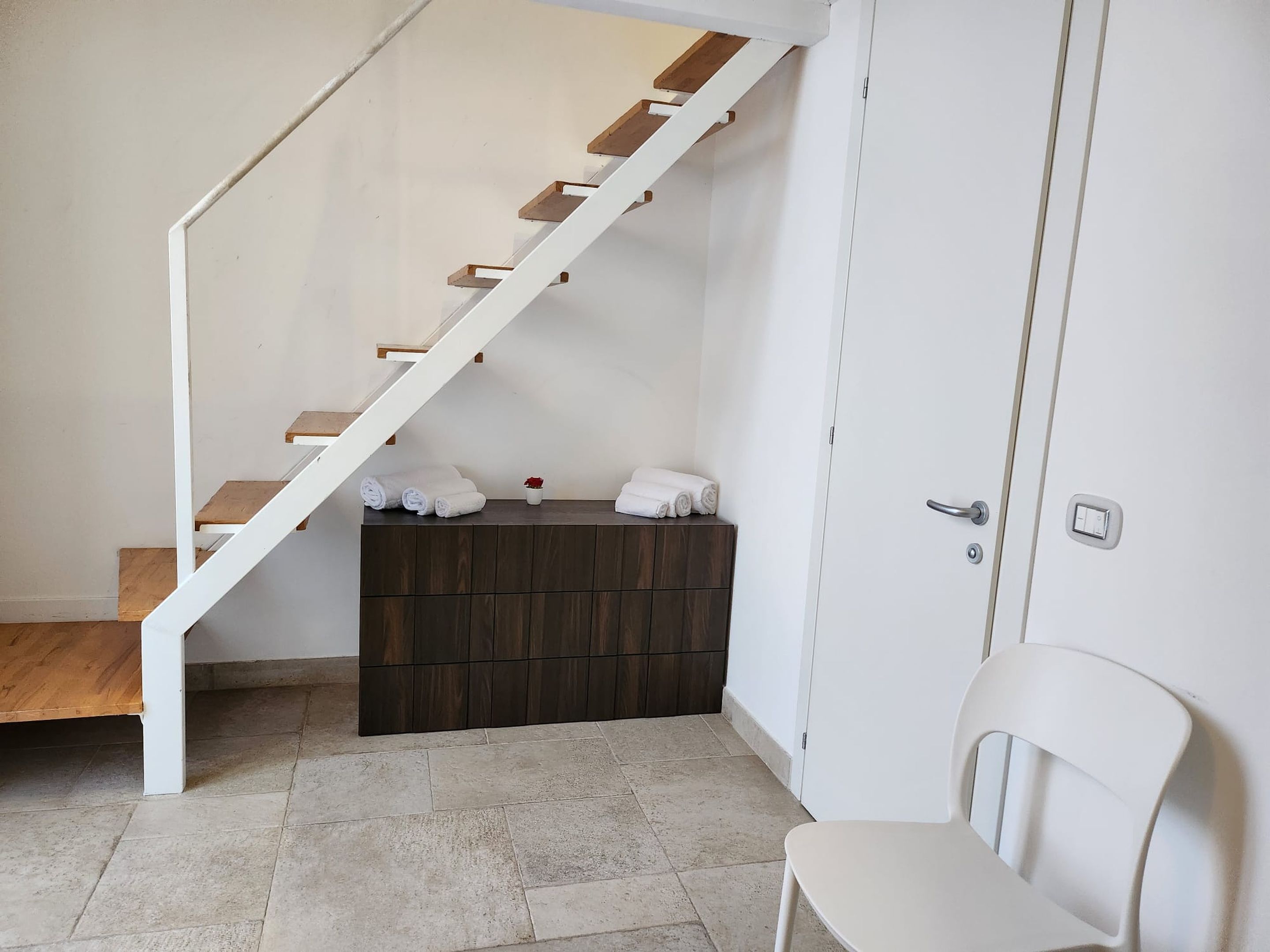 A clean, modern bathroom with a white bathtub, a wooden bench, and a white chair.