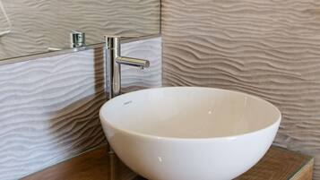Un baño moderno con un lavabo de cerámica blanco, un grifo cromado y una pared con textura.