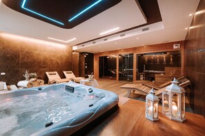 Une salle de spa moderne dotée d’un jacuzzi, de revêtements de sol en bois et de fauteuils confortables.