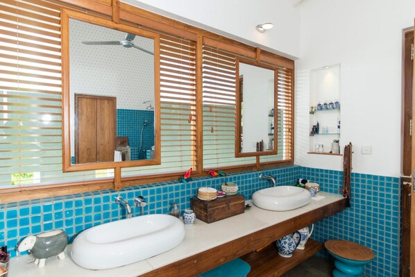 Un baño con dos lavamanos, un mueble de tocador de madera, un espejo grande y un respuesto de azulejos azules.