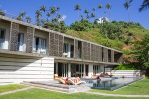 A modern hotel with a swimming pool, outdoor seating, and a view of palm trees. - Modern Beach Villa With Roof Garden (Talalla)