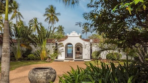 A white building with a tiled roof, surrounded by lush greenery and palm trees. - Spectacular Hilltop Beach Villa Located Next To A Surf Break (Nilwella)