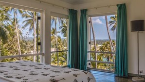 A bedroom with a bed, large windows, and a view of palm trees and a beach. - Spectacular Hilltop Beach Villa Located Next To A Surf Break (Nilwella)