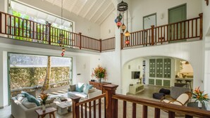 Un amplio salón con techos altos, una escalera de madera y vista a una pared de piedra.