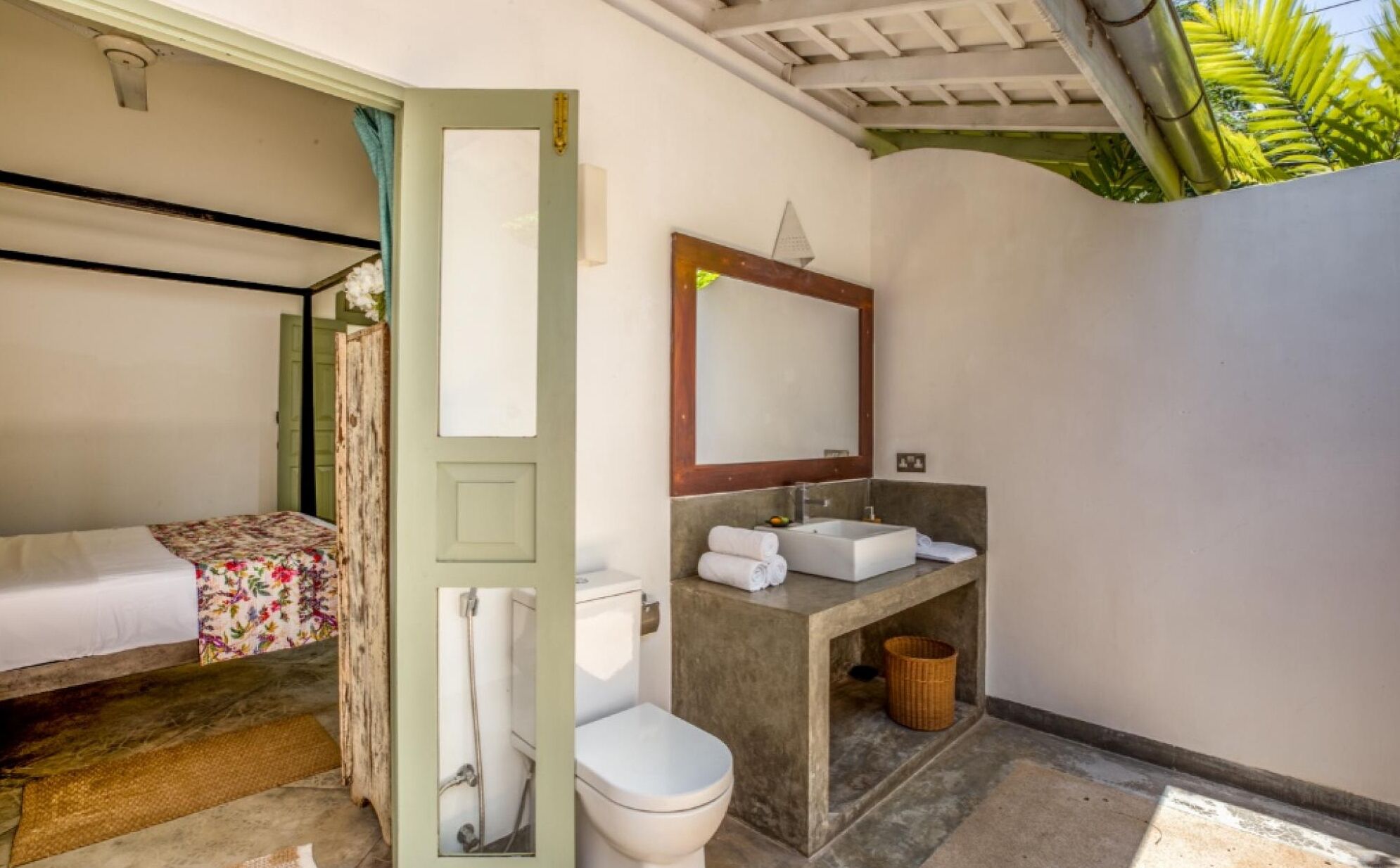 A small, compact room with a bed, a toilet, and a sink.