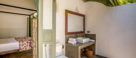 A small, compact room with a bed, a toilet, and a sink.