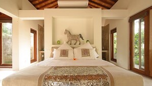 Ein geräumiges Schlafzimmer mit einem großen Bett, einer dekorativen Pferdeskulptur und einem einzigartigen Teppich mit Mosaikmuster.
