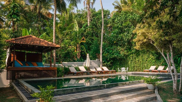 A pool area with lounge chairs, a small gazebo, and steps leading into the water. - Refurbished Family Village House With Private Pool (Koggala)