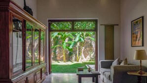 A room with a large window, a sofa, a table, and a cabinet. - Refurbished Family Village House With Private Pool (Koggala)