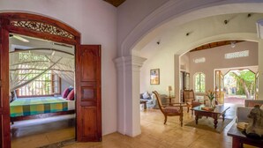 A spacious living area with a large wooden door leading to a balcony, a seating area with a coffee table, and a view of the outdoors. - Refurbished Family Village House With Private Pool (Koggala)